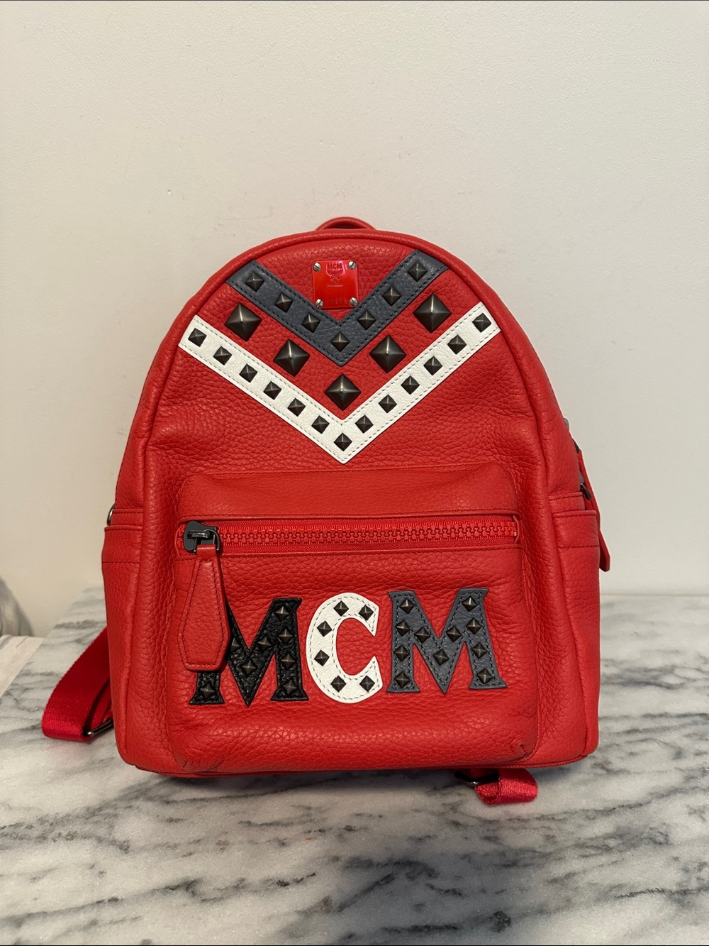 limited-edition MCM × EKOCYCLE x Will.i.am red Studded Leather Backpack.